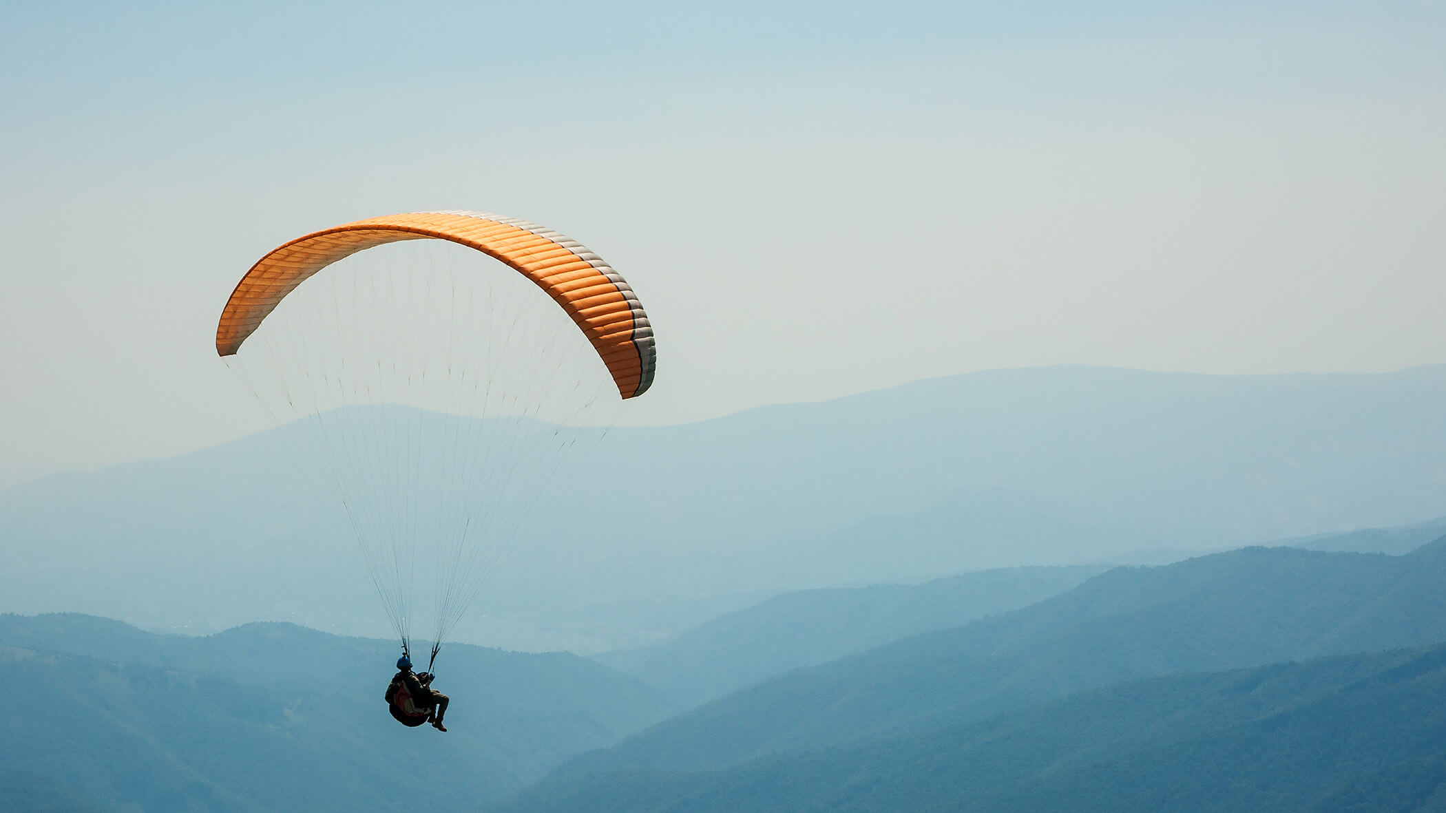 A paraglider flying over the South Tyrolean mountains - OLM Nature Escape