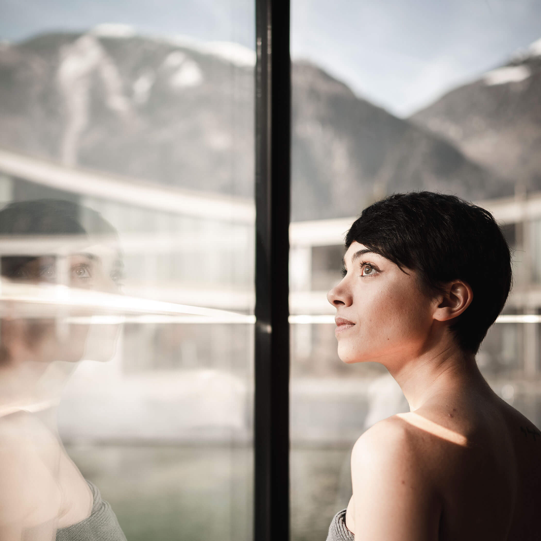 Donna che guarda dalla sauna verso il cortile - OLM Nature Escape